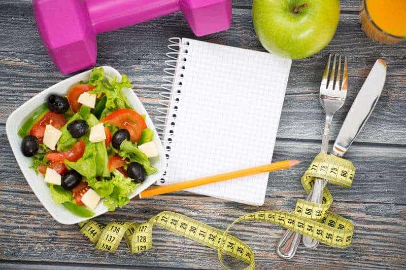 bowl of salad and notebook to track healthy eating