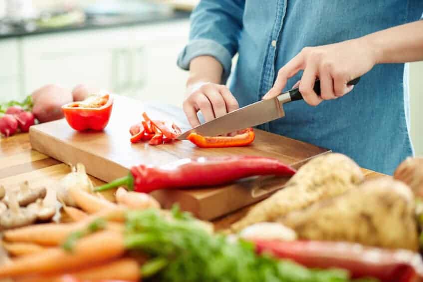 person cutting up a nutritious red pepper