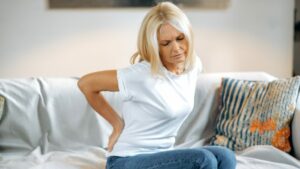a woman holding her lower back that is suffering from fibromyalgia symptoms
