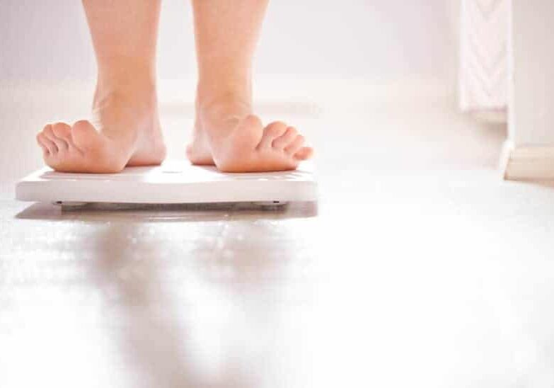 person weighing themselves on a bathroom scale